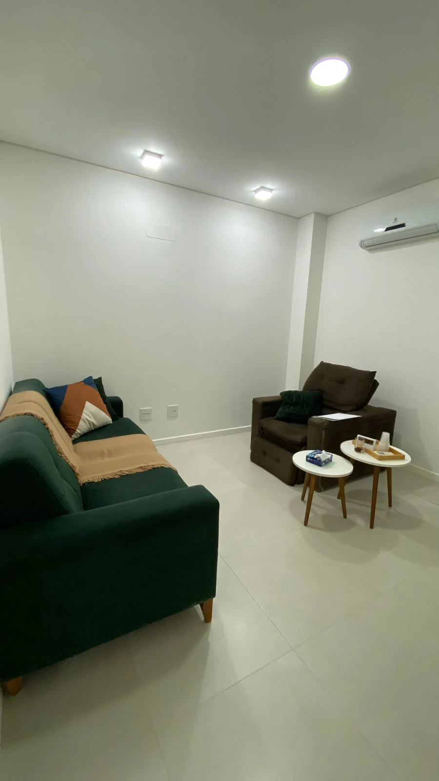 Consultório de psicoterapia em Coqueiros, com sofá verde e poltrona de atendimento